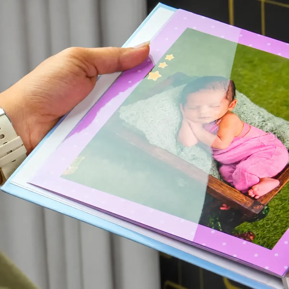 Hand holding a glossy laminated album page