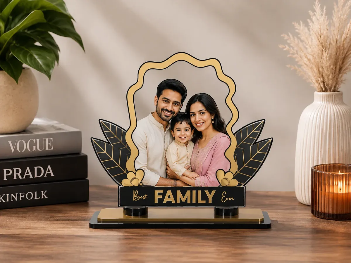 Miniature acrylic photo stand on a desk — a family portrait cut to shape, framed in gold leaves on a black base — Siri Print World, Palakollu